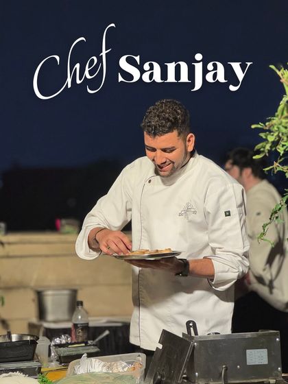 Chef Sanjay carefully plating appetizers at an outdoor event. Our chefs work in any environment to deliver exceptional food.