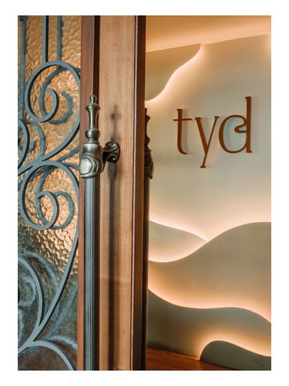 A detail shot of the entrance, where an ornate wooden door with wrought iron details meets a modern, backlit wall feature. This juxtaposition of classic and contemporary is a hallmark of my design style.