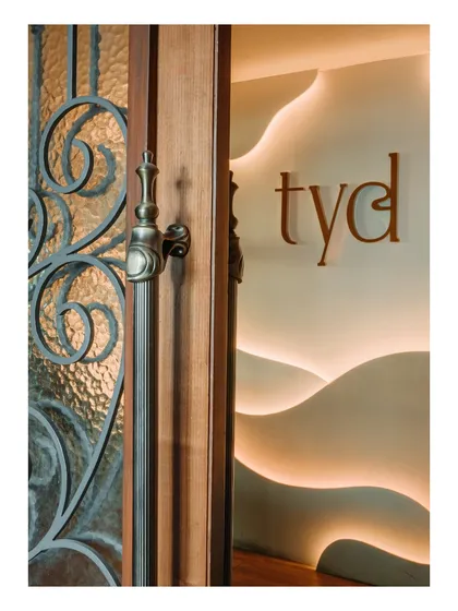 A detail of the entrance, where an ornate wooden door handle contrasts with the modern, backlit signage. This juxtaposition of traditional craftsmanship and contemporary design is a hallmark of my style.