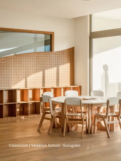 A classroom at Vedanya School, Gurugram, bathed in natural light. The design uses simple wooden furniture and a pegboard wall for flexible storage, creating a calm and adaptable learning space.