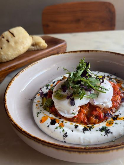 A beautiful bowl of Balkan Eggs, garnished with fresh microgreens. It's a flavorful and satisfying vegetarian brunch option.