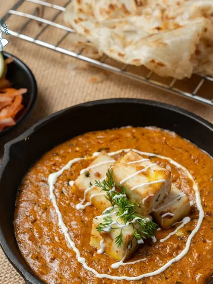Another view of my signature Paneer Lazeez served in a cast-iron pan with fresh cream and herbs, paired with hot Laccha Parathas. This dish is a perfect centerpiece for any vegetarian main course spread.