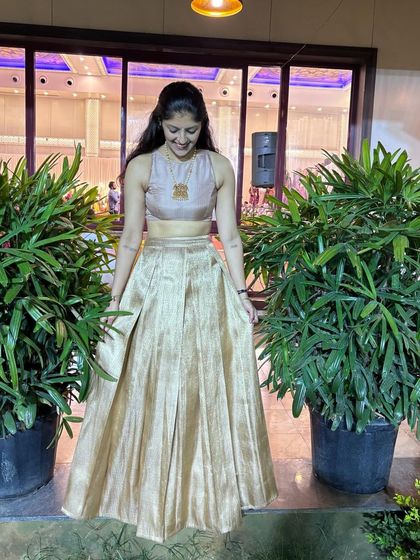 A simple and elegant lehenga set in a muted gold fabric. The sleeveless crop top and pleated skirt create a graceful silhouette.