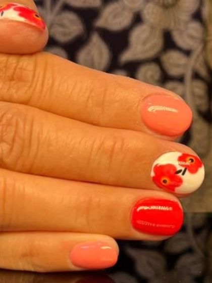 A vibrant and artistic design with hand-painted red poppy flowers on short, colorful nails.