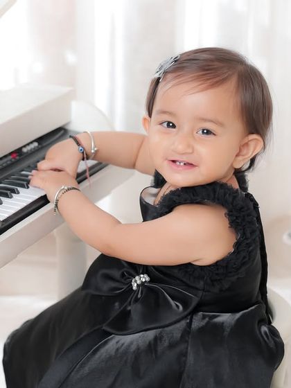 A little pianist at work. This elegant portrait in a black dress at a white piano is a timeless and sophisticated way to capture a milestone.