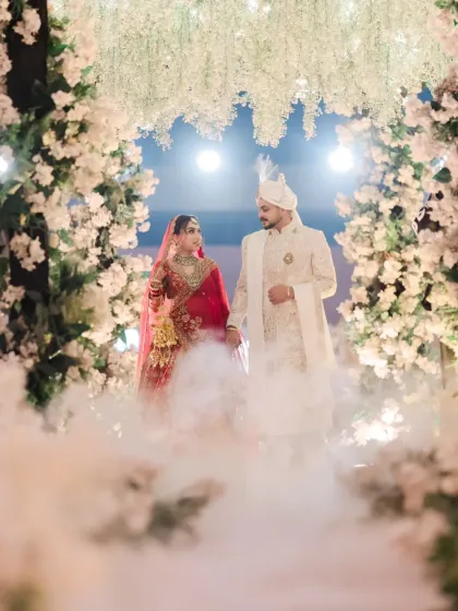 A magical wedding portrait of the couple standing under a floral arch, surrounded by ethereal smoke.