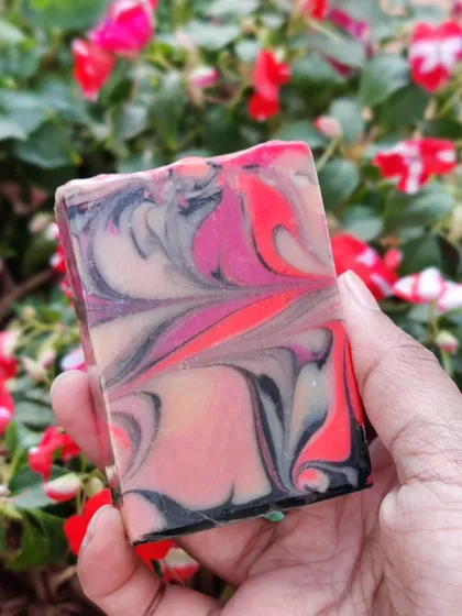 A close up of one of my signature swirl soaps. I love playing with colors and creating these intricate patterns. This bar, with its vibrant pinks and deep blacks, feels like a little piece of abstract art you can hold in your hand.