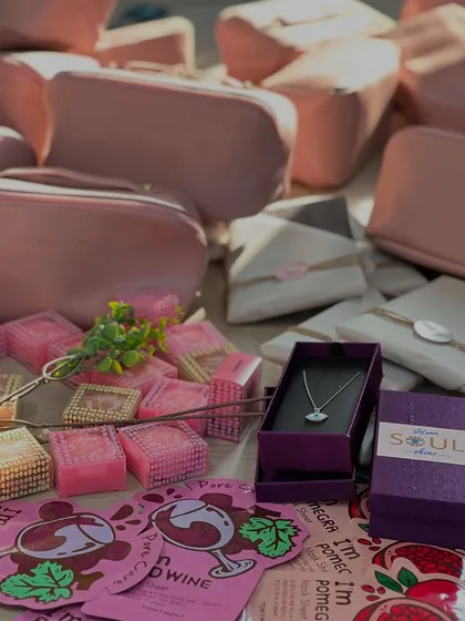 A flat lay of some of the items included in our Women's Day hampers, such as personalized pouches, sheet masks, and delicate evil eye necklaces.