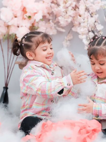 Twin girls playing in a sea of soft clouds and flowers. Our themed studio sessions are a magical way to capture your children's imagination.