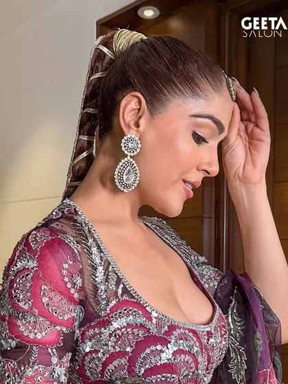 A side profile of our modern bridal hairstyle. The intricate, wrapped ponytail is a unique and stylish choice for a bride who wants to make a statement, while the makeup remains soft and glowing.