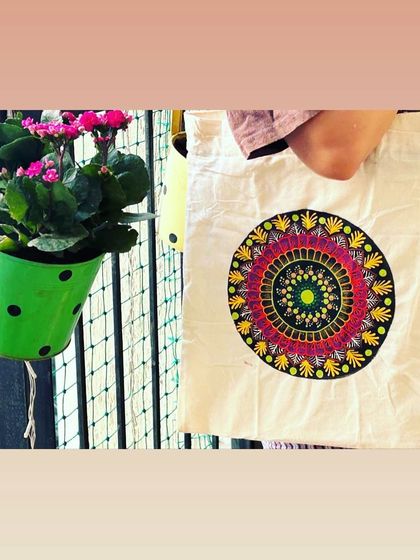 Art you can carry with you. This photo shows a completed, colorful mandala design painted on a white tote bag.