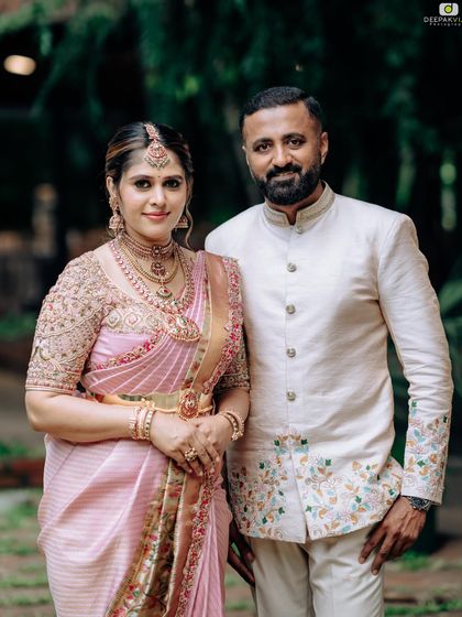 A formal portrait of my husband and me. His cream bandhgala jacket features subtle floral embroidery that echoes the motifs on my pink saree.