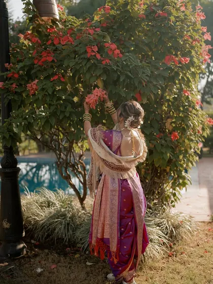 A beautiful shot from the back, showcasing the traditional nine-yard saree and the elegant floral bun, a classic hairstyle for a Maharashtrian bride.