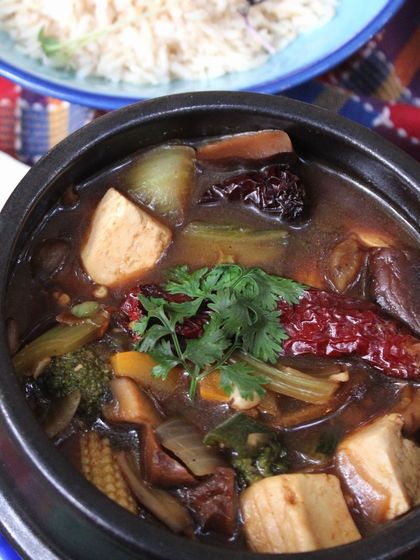 Our Sichuan Claypot is a signature dish I crafted myself. It's a spicy Asian stew brimming with tofu, mushrooms, and burnt chilies, served with brown rice for a complete, flavorful meal.