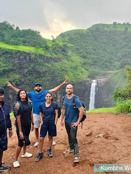 A small group posing with the Kumbhe waterfall in the background.