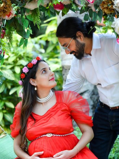 A close-up, intimate moment between a couple during their outdoor shoot. The mom-to-be wears a floral crown, and their loving gaze says it all.