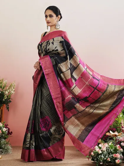 A saree with a contemporary print featuring checks, stripes, and floral motifs in a black and pink color palette.