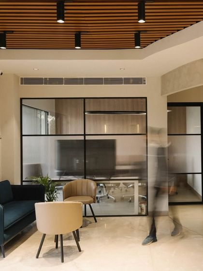 The waiting area at the Vision office features a comfortable seating arrangement with a view into the glass-walled meeting rooms. The design promotes transparency and a sense of openness.