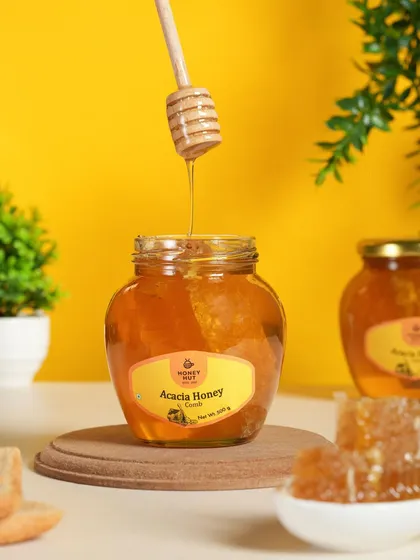 A clean, bright shot of honey being drizzled into a jar of acacia honey. The focus on the golden color and thick texture makes the product look premium and pure.
