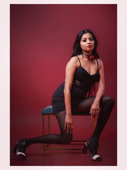 A glamorous and dramatic studio portrait. The rich red background and the model's pose create a sense of intimacy and intensity, perfect for a beauty or fashion editorial.