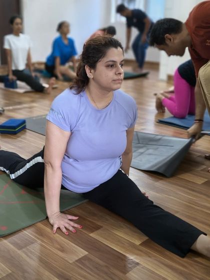 A student works on her splits with the support of a folded mat, a great way to ease into the full Hanumanasana posture.