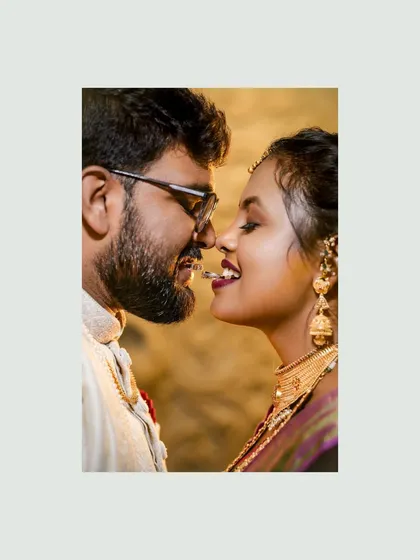 A playful and intimate shot of the couple with the engagement ring held between their teeth.