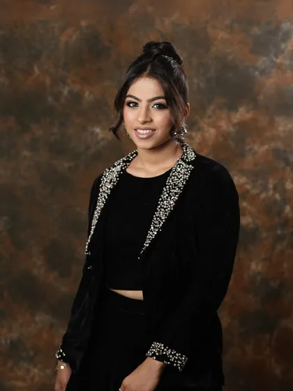 A full portrait of the second look, showcasing the complete styling. The elegant updo and embellished outfit work together with the makeup to create a polished and professional image.