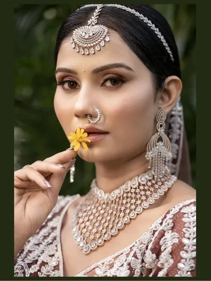 A modern bridal portrait with a touch of tradition. The bride holds a yellow flower, adding a pop of color that contrasts beautifully with her diamond jewelry.