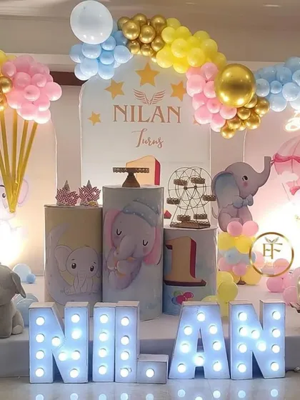 An adorable elephant-themed first birthday with a pastel color scheme. The decor includes hot-air balloon props, marquee letters, and custom-printed pedestals, creating a dreamy atmosphere.