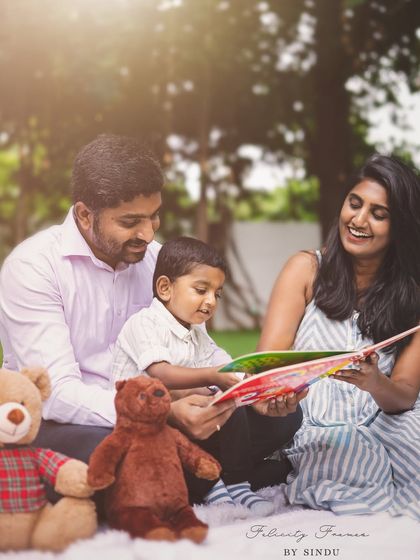 A family shares a storybook together during a picnic-style outdoor photoshoot. This gentle, candid moment is a beautiful example of capturing quiet family connections.