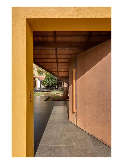 A large, pivoting door marks the entrance to one of the new pavilions. The use of bold color and simple forms distinguishes the new architecture from the old.