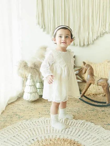 Happy First Birthday to this gorgeous girl. Standing tall in her beautiful dress, this shot captures a huge milestone in a baby's first year, perfect for a birthday photoshoot.