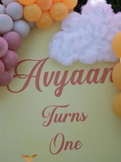 A close-up of the "Avyaan Turns One" sign from the sunshine-themed party, showing the custom typography and cloud details.