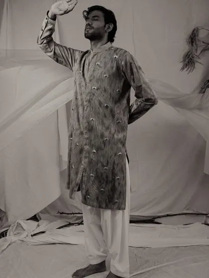 A dramatic, full-length black and white photo of a male model in a printed kurta. The pose and monochrome treatment give the image a timeless, classic feel.
