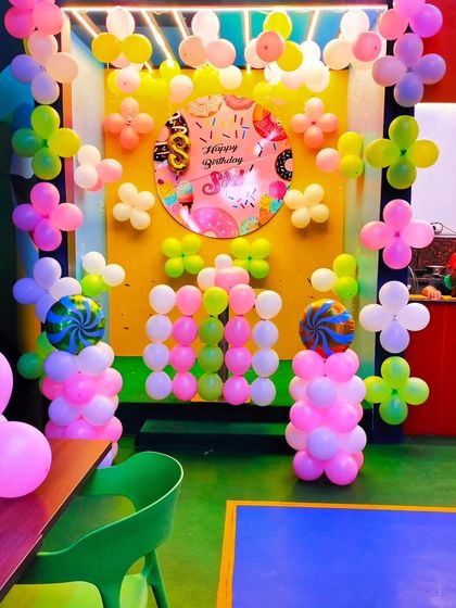 A fun and sweet donut-themed birthday backdrop in a cafe. The colorful balloon arrangement and custom-printed backdrop create a cheerful spot for photos.