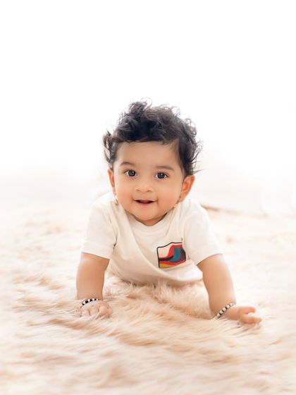 A solo portrait of the adorable baby brother from the sibling session. His bright smile and curly hair are just precious.