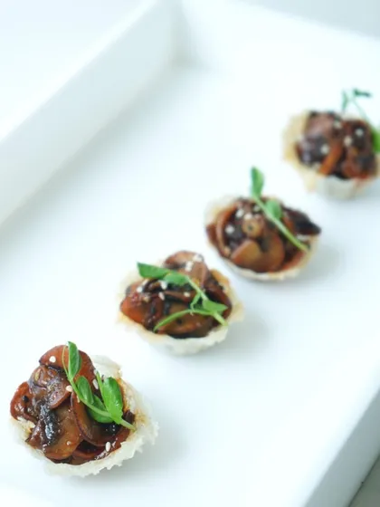 Asian-inspired mushroom tartlets with a sesame garnish. These bites are part of our diverse menu offerings, which include a range of international cuisines to suit any event theme.