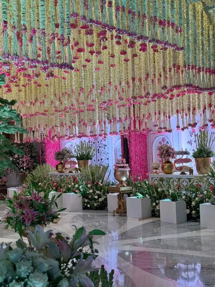 A low-angle view of the floral paradise, emphasizing the scale of the cascading ceiling installation and the lush arrangements that define the walkway. 🌸✨