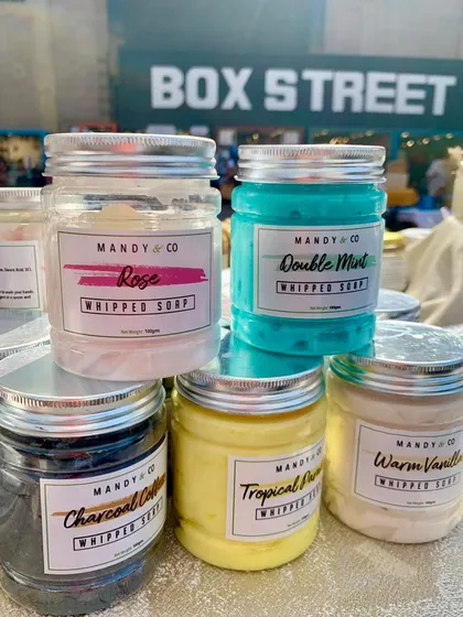 A display of my handcrafted whipped soaps in various scents and colors, from Rose and Double Mint to Charcoal Coffee.