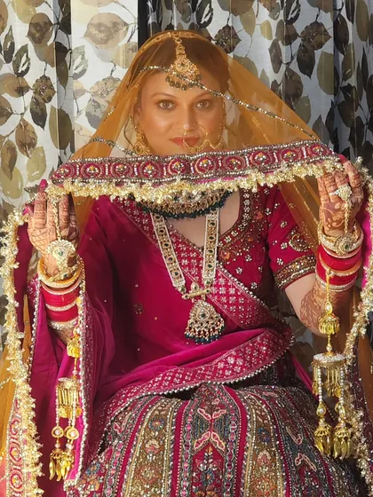 A regal pose showing the complete bridal attire. The makeup, with its classic red lip and defined features, perfectly complements the traditional jewelry and outfit.