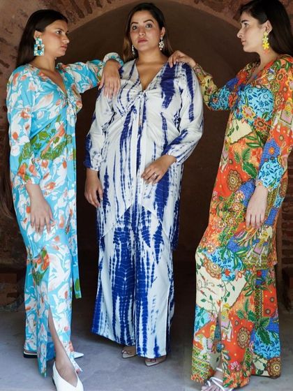 A trio of models showcasing a collection of vibrant, bohemian-style printed dresses and kaftans.