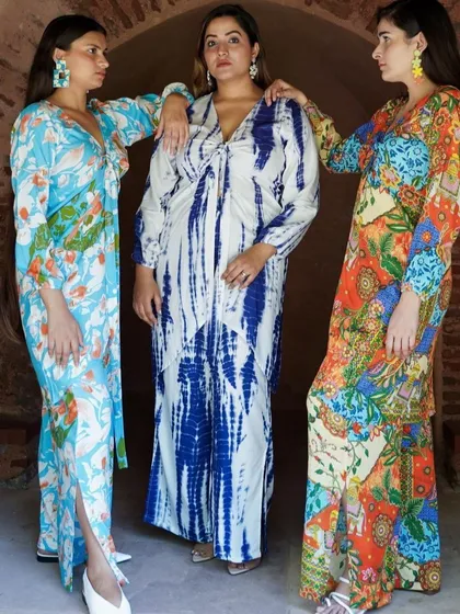 A trio of models showcasing a collection of vibrant, bohemian-style printed dresses and kaftans.