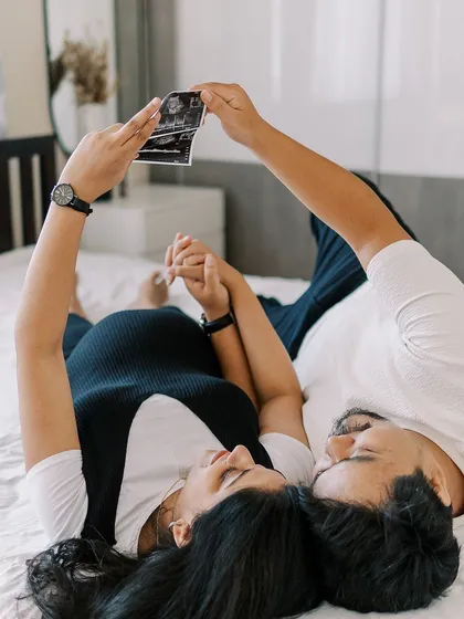 Bringing your ultrasound scan to the session is a wonderful way to make the moment even more real. Here, the couple lies together, looking at the very first picture of their baby, a simple prop that tells a powerful story.