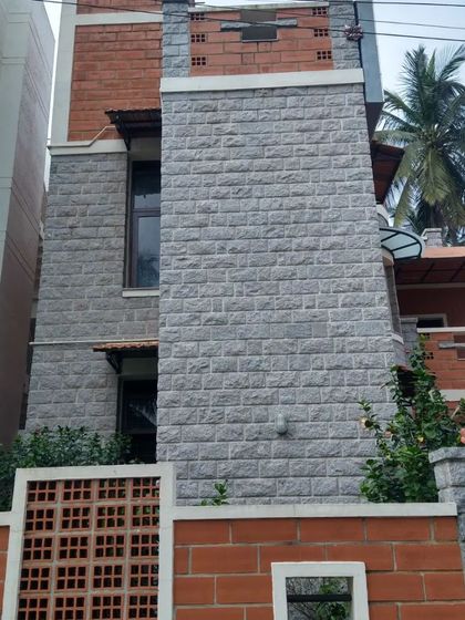 A tall, chimney-like structure clad in stone, creating a strong vertical element on the home's facade.