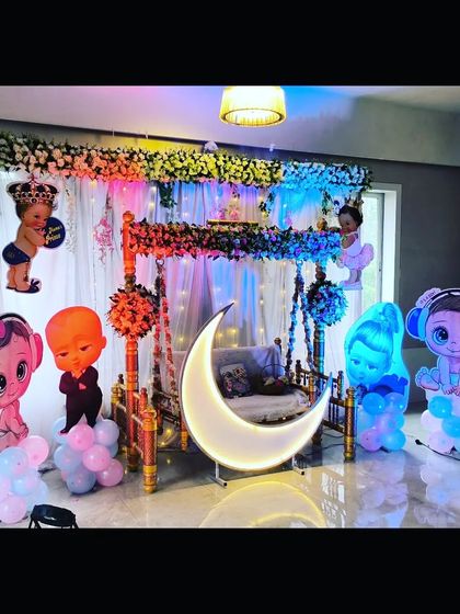 A fun and colorful baby shower decoration with a mix of cartoon characters, a lighted moon, and a traditional swing, perfect for a lively celebration.