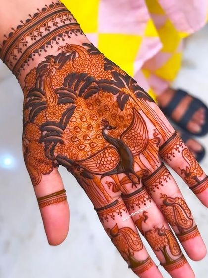 A close-up of the hand featuring a dense and beautifully shaded peacock design, a classic element in traditional Indian mehandi.