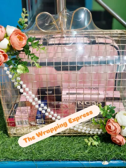 A trousseau gift basket for a bride, elegantly packed in a gold wire frame basket. It includes a vanity case filled with MAC cosmetics and is decorated with flowers.