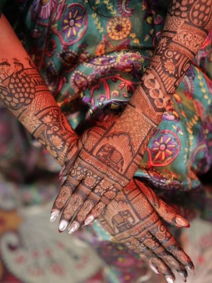 A close-up of a bride's hands, showcasing the detailed elephant motifs and traditional patterns of her bridal mehandi.