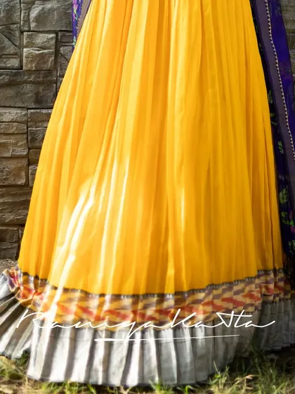 A detail of the mustard yellow pleated skirt, featuring a unique border with Ikat and silver tissue frills.