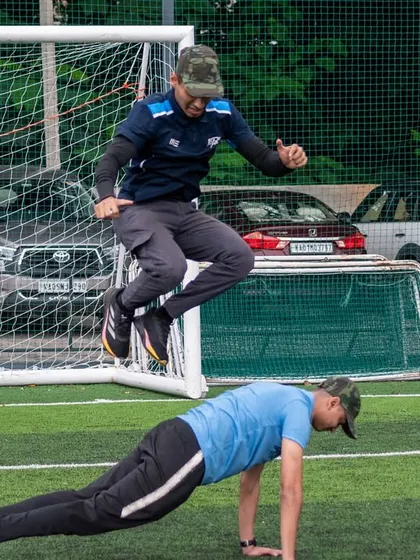 A coach demonstrates a partner-assisted jump during our military-style workout. This shows the fun, challenging, and team-oriented nature of our community events.